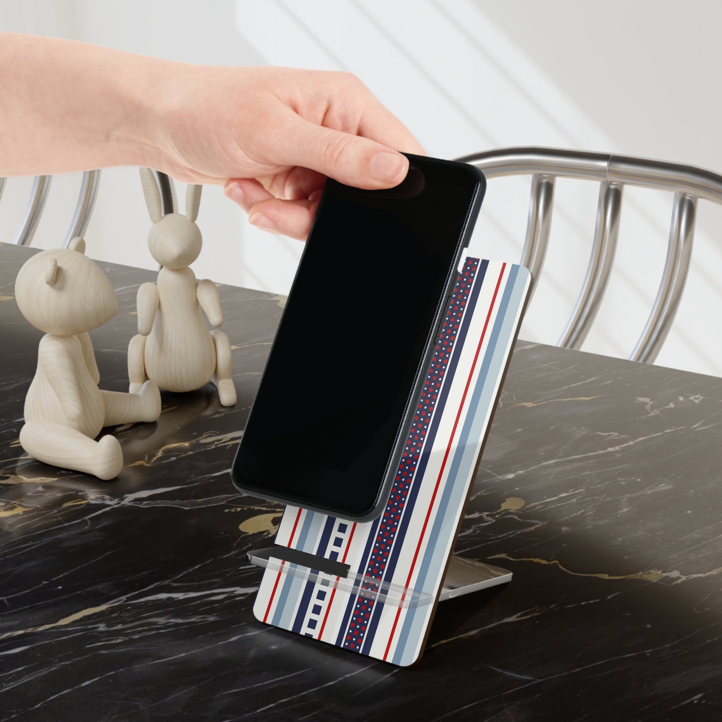 Phone being placed on a decorative phone stand with marble surface and rabbit figurines in the background