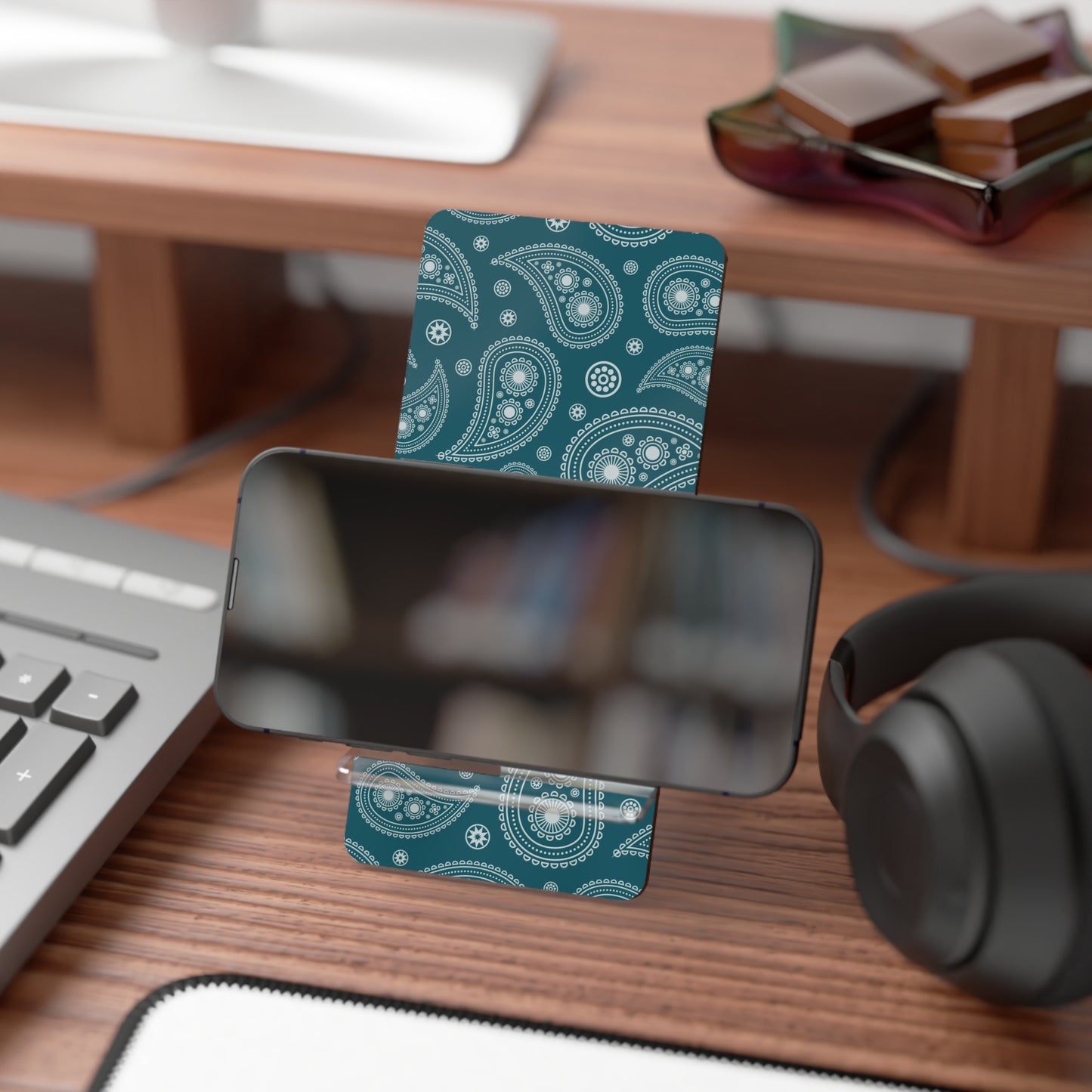 Teal paisley patterned card on a desk with a phone, keyboard, and headphones.