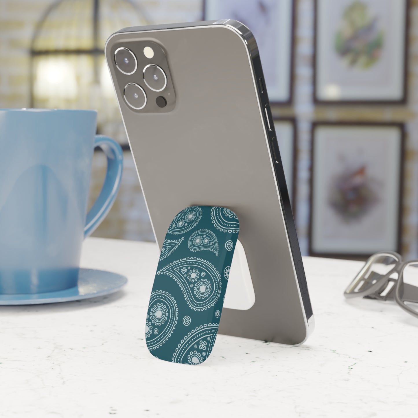 Phone case with blue paisley design on a white surface with a blurred background