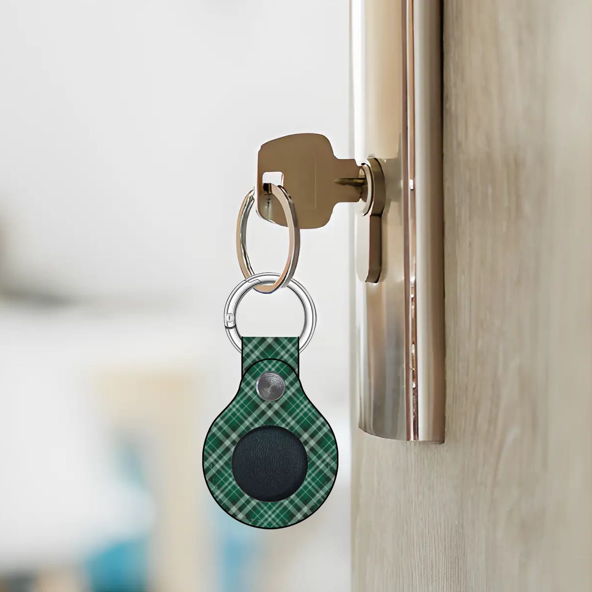Green plaid keychain attached to a door handle with a blurred background | Casenari