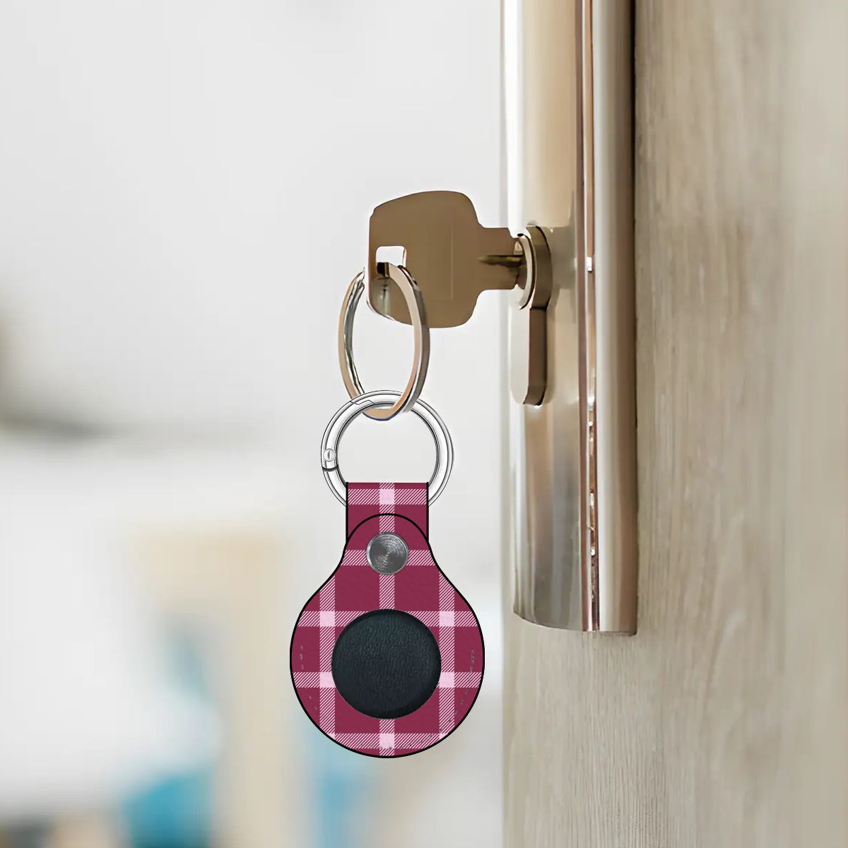 Pink plaid keychain attached to a door handle with a blurred background
