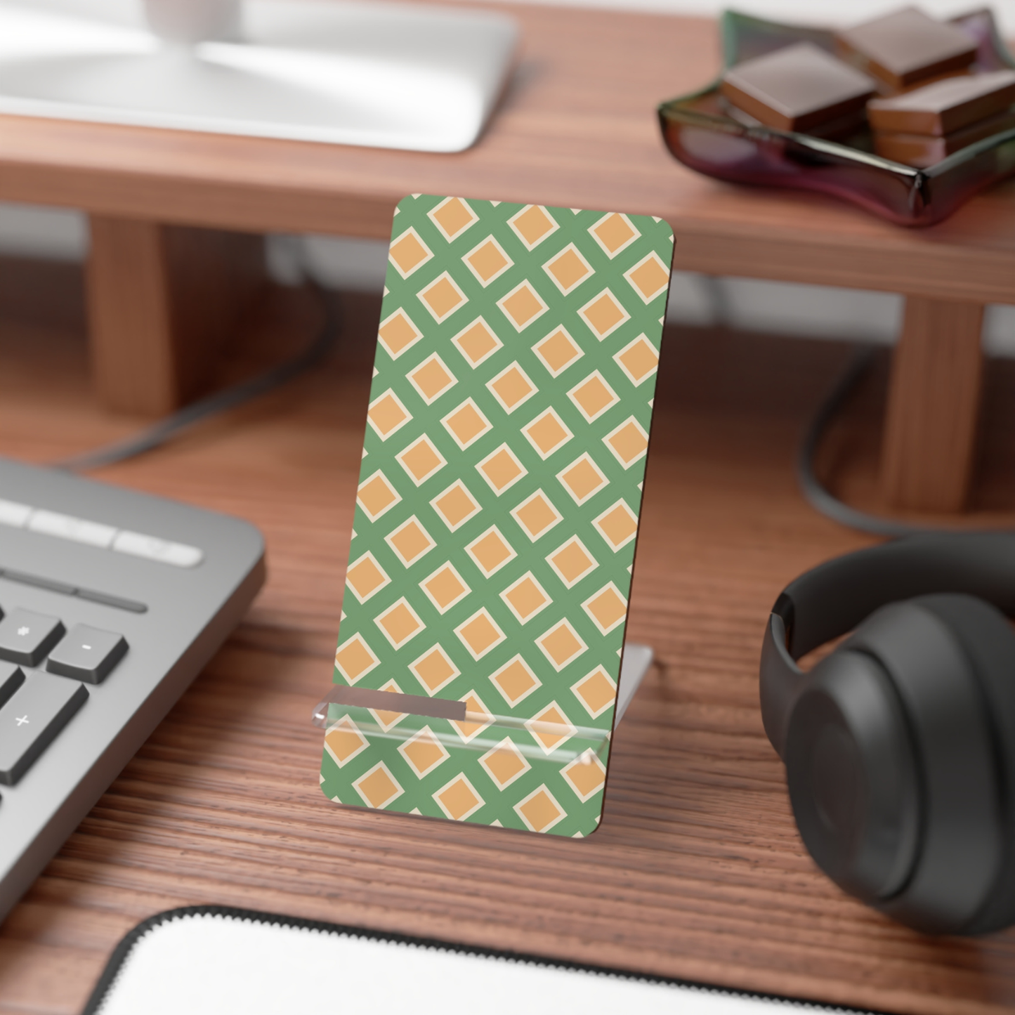 Desk setup with a green and orange patterned phone stand, keyboard, mouse, and headphones.