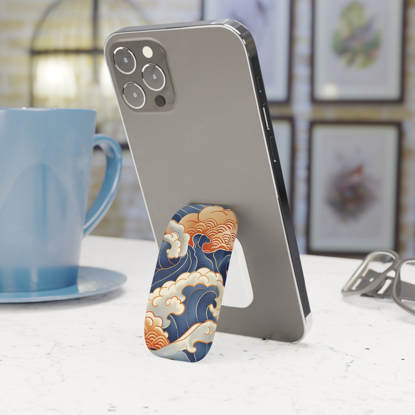 Phone case with wave design on a phone stand next to a blue mug.