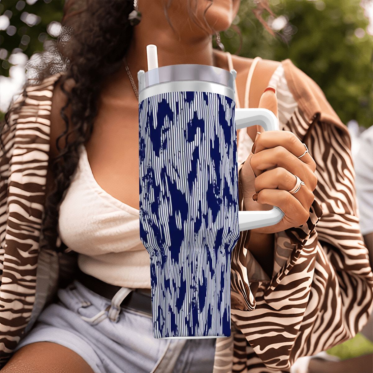 Person holding a blue and white patterned tumbler outdoors