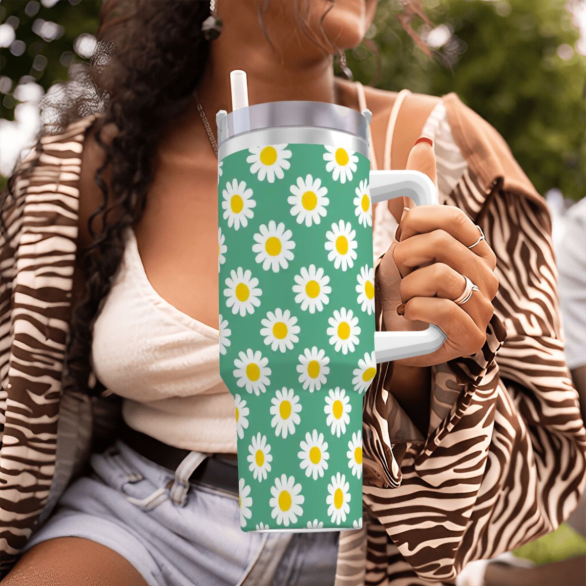 Person holding a tumbler with daisy pattern outdoors