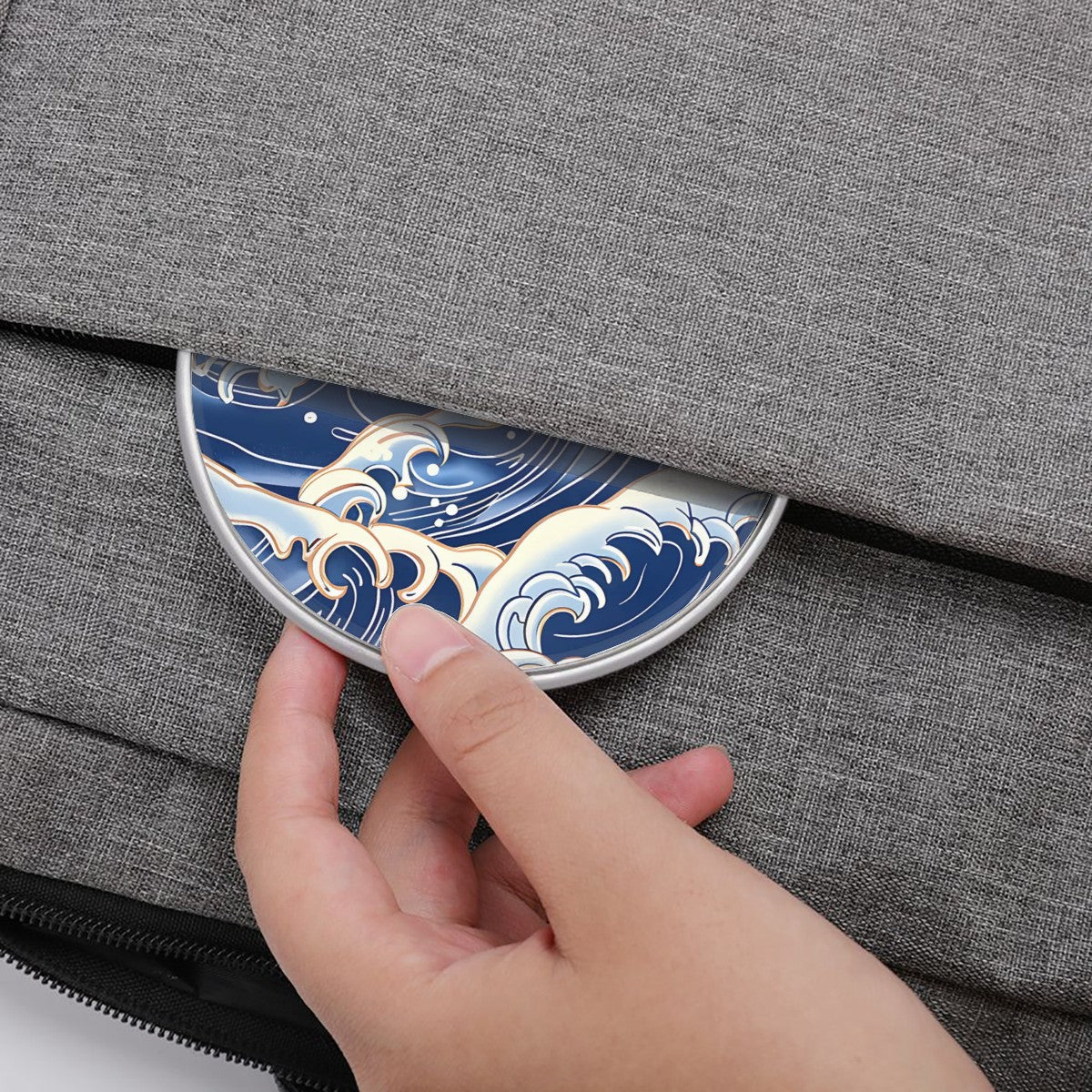 Hand pressing a decorative blue and gold wave design on a gray fabric surface | Casenari