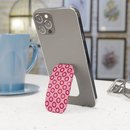 Phone with a pink stand on a table next to a blue mug