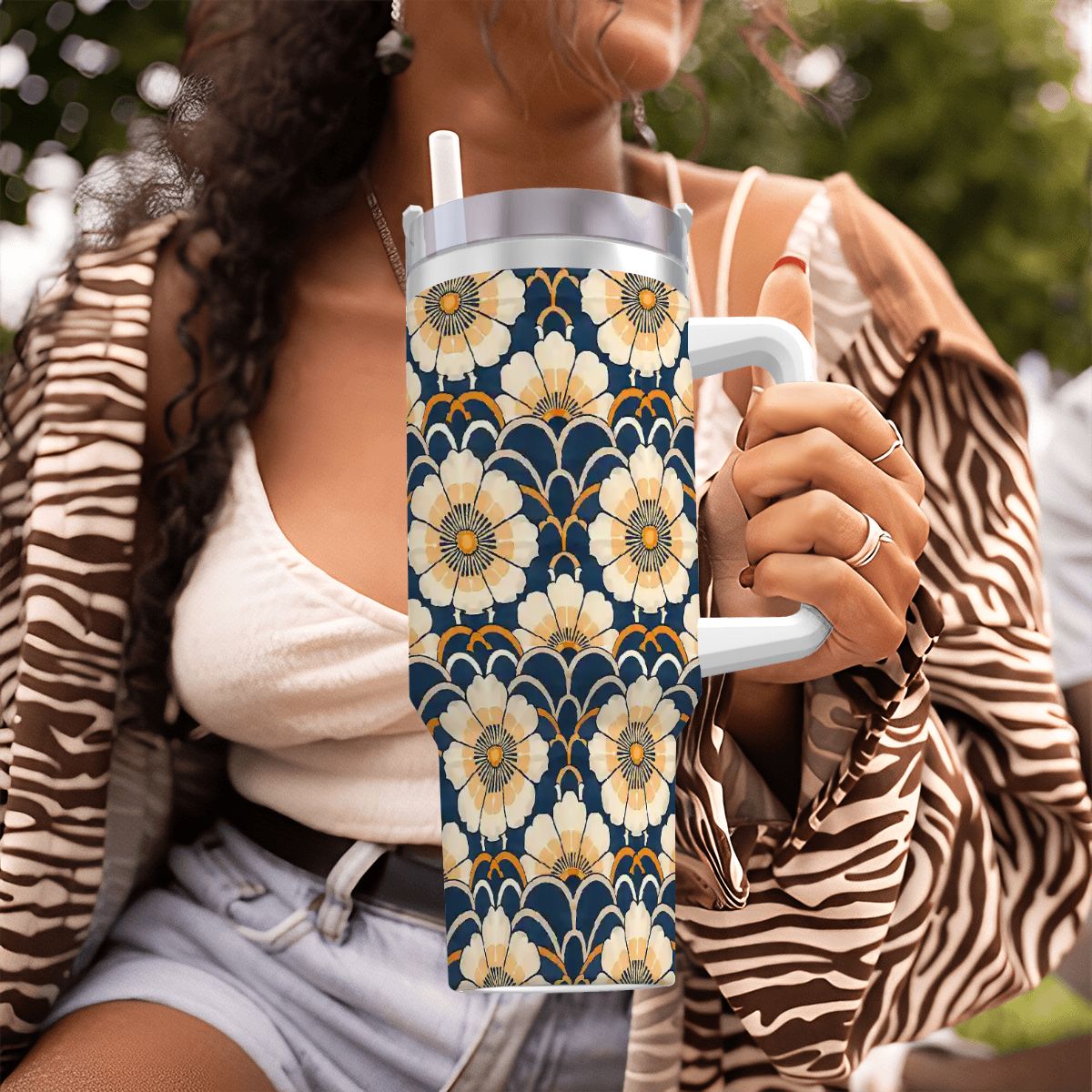 Person holding a floral-patterned tumbler with a blurred background