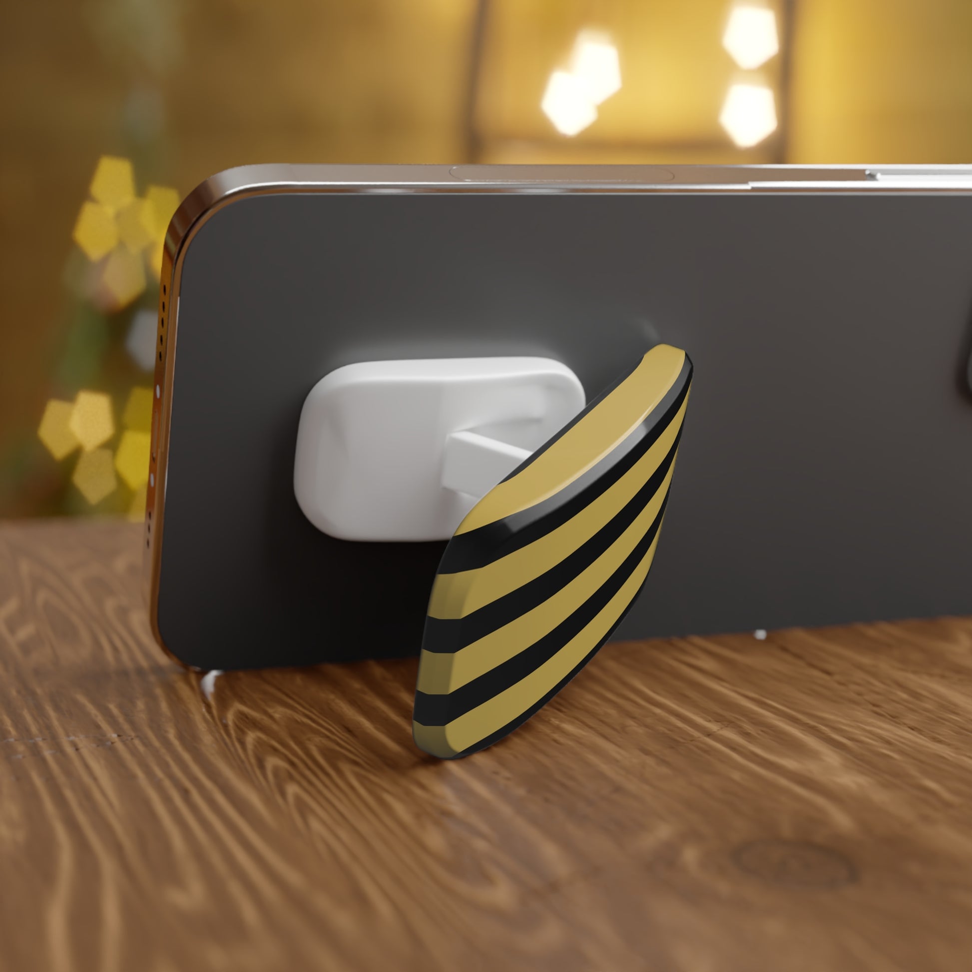 Phone grip with yellow and black striped design on a wooden surface