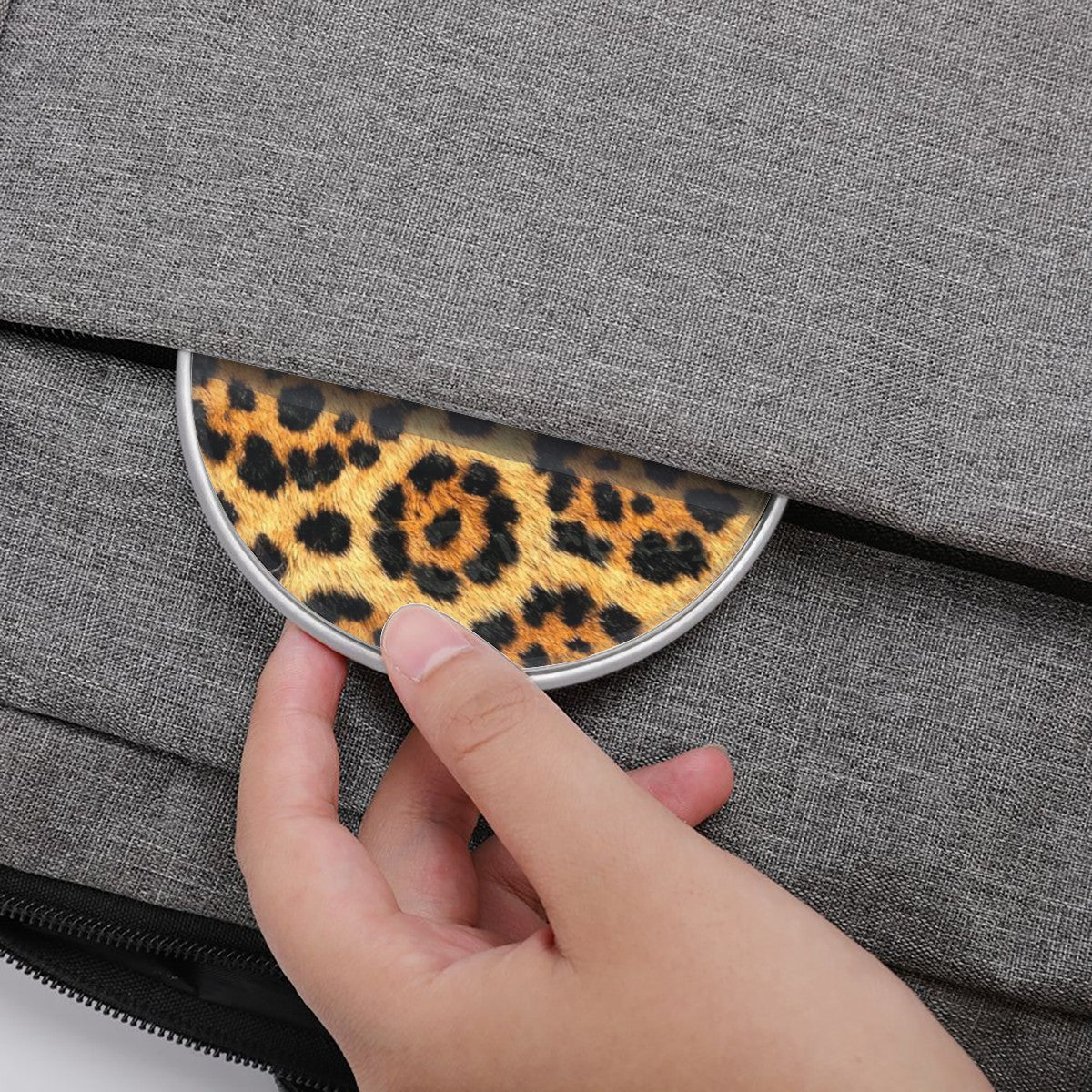 Hand placing a leopard print coin purse into a gray fabric bag.