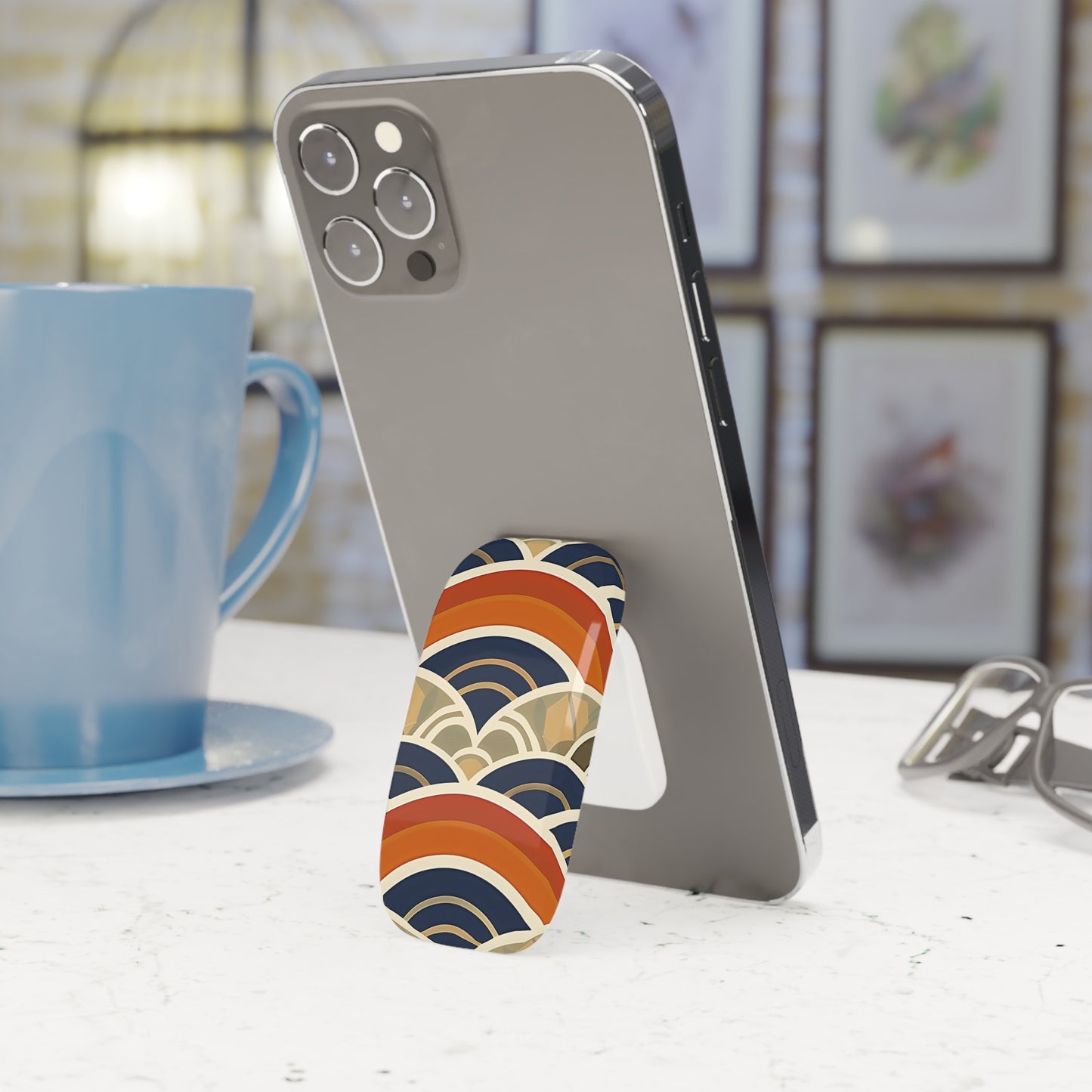 Phone with a colorful stand on a table next to a blue mug