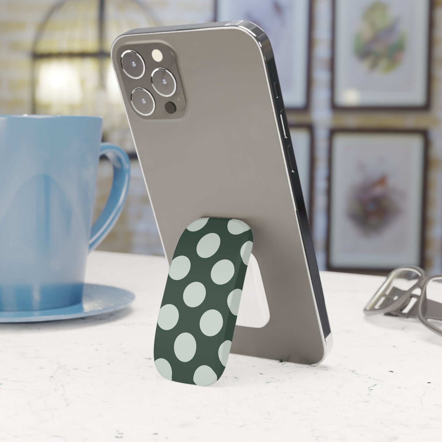 Phone with a polka dot stand on a table next to a blue mug