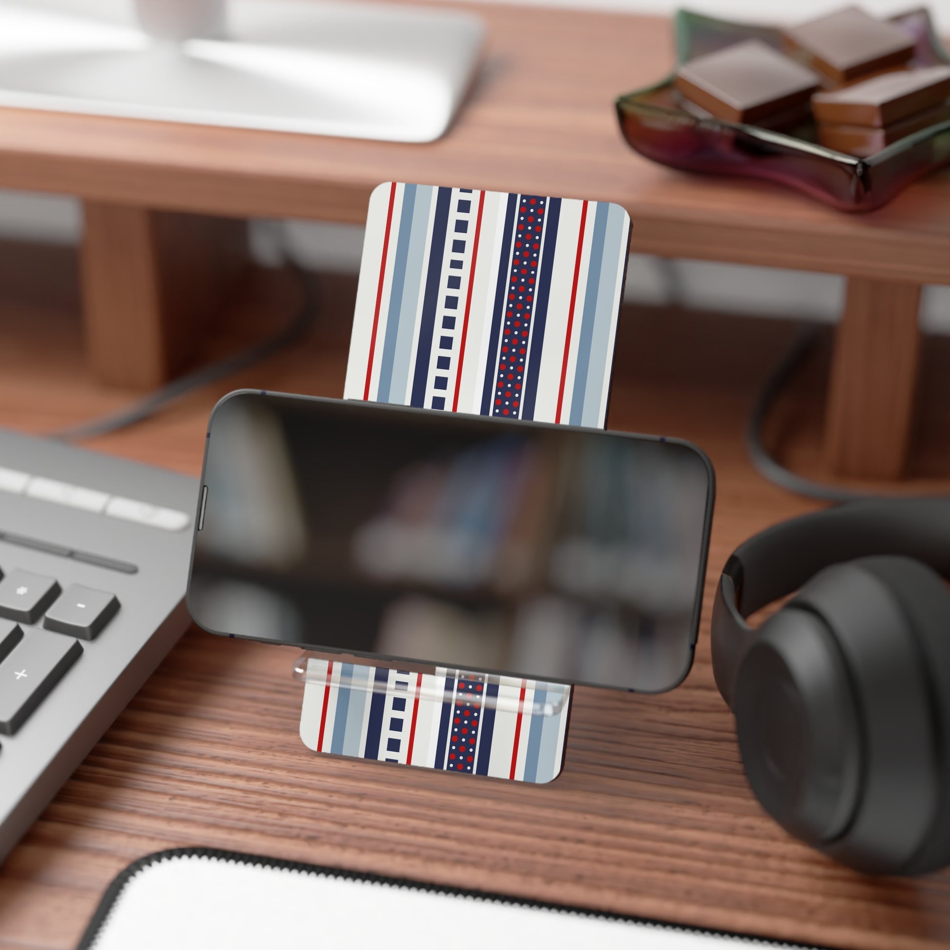 Phone stand with striped design on a desk with keyboard, mouse, and headphones.