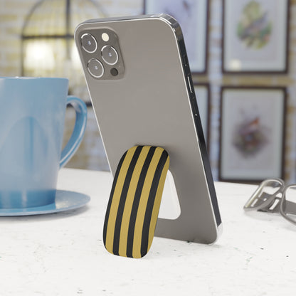 Phone with a black and yellow striped stand on a table next to a blue mug.