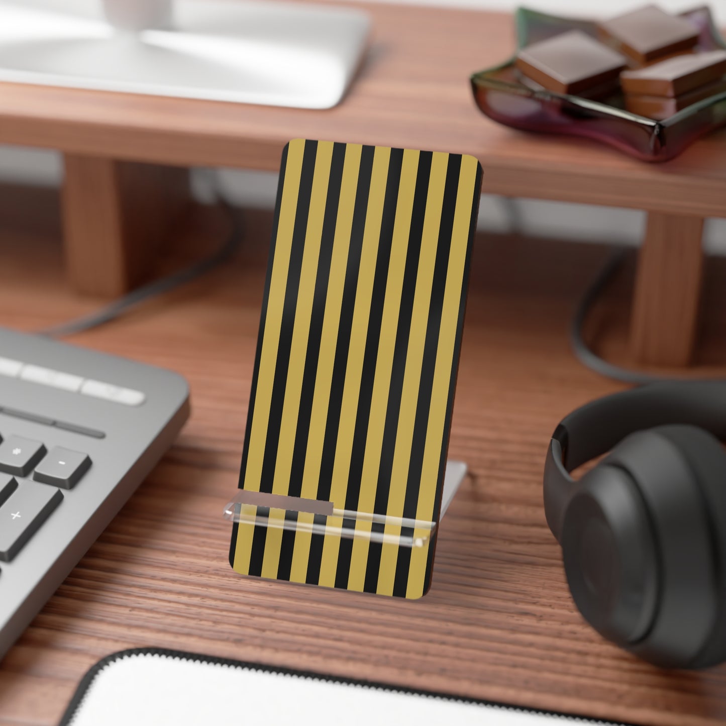 Black and yellow striped phone stand on a desk with a keyboard, mouse, and headphones.
