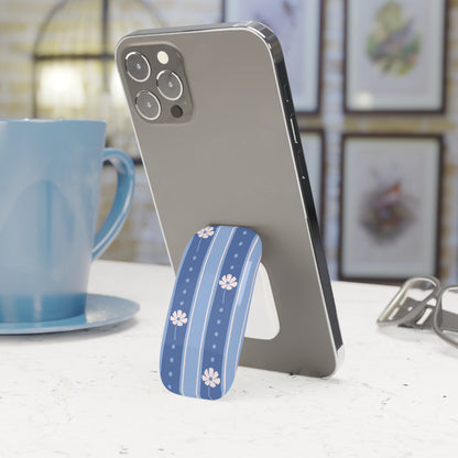 Phone with a blue floral phone stand on a table next to a blue mug.
