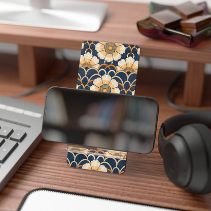 Phone stand with floral design on a desk with keyboard, headphones, and books.
