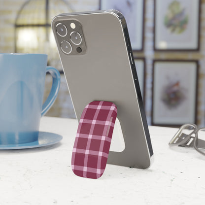 Phone stand with plaid design holding a smartphone next to a blue mug on a table.