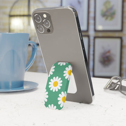 Phone with a daisy pattern stand on a table next to a blue mug.