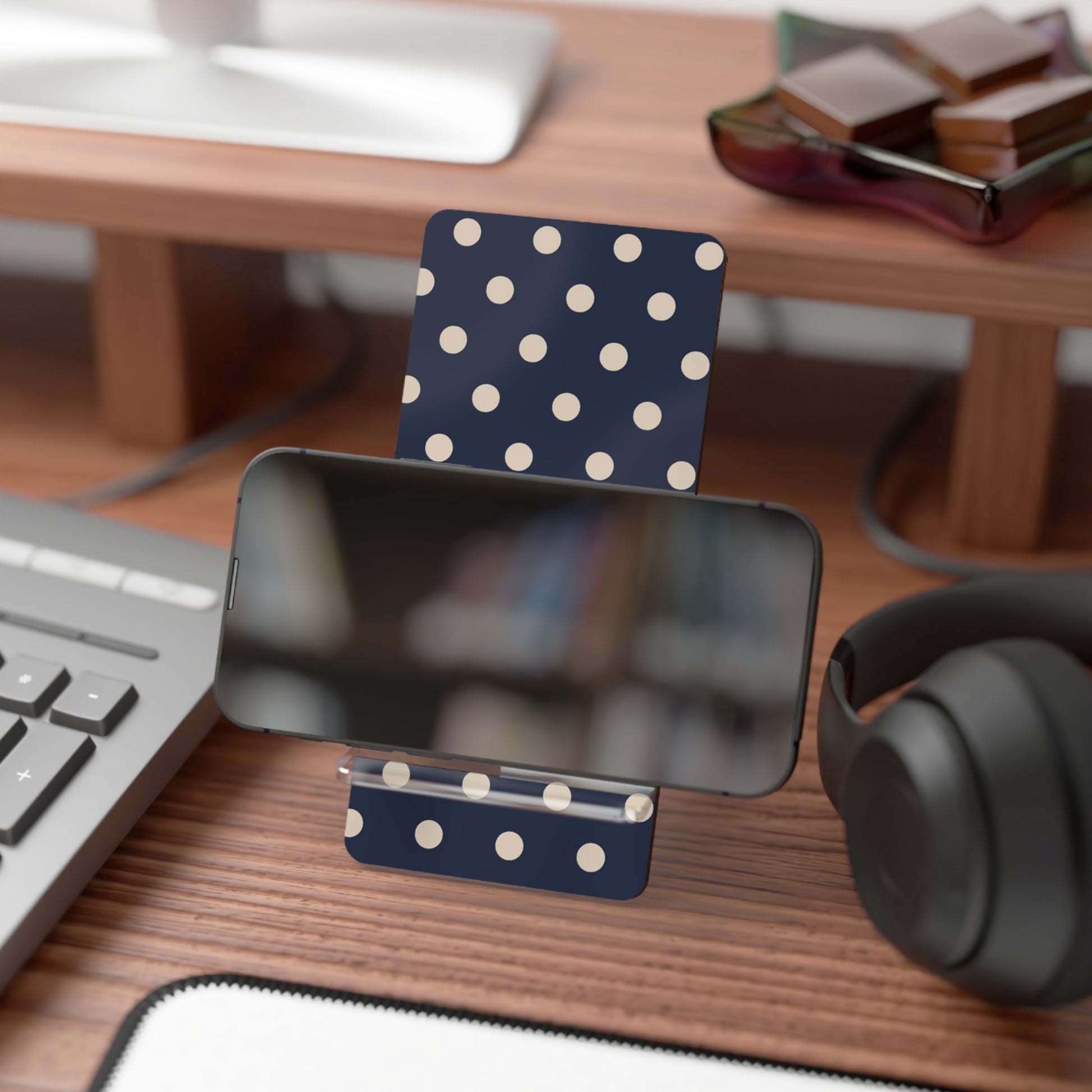 Polka dot phone stand on a desk with a smartphone, keyboard, and headphones.