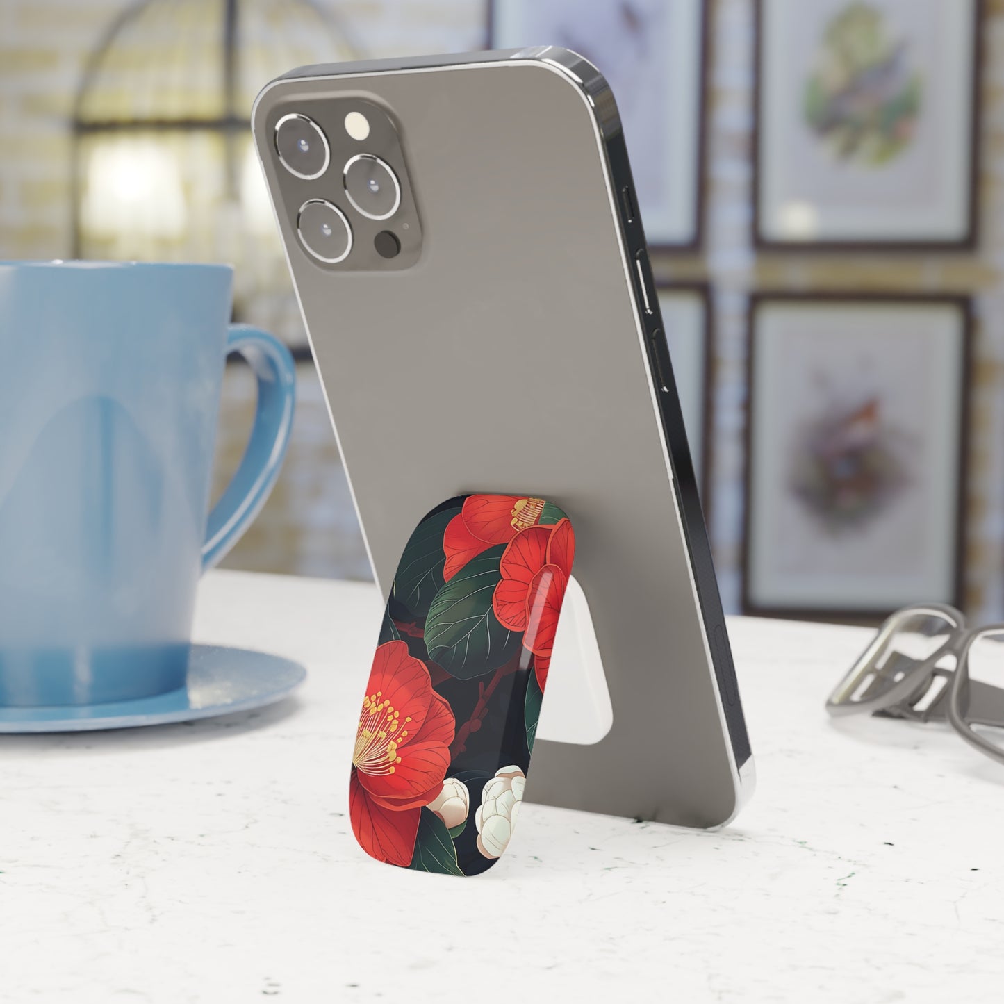 Phone with floral stand on a table next to a blue mug