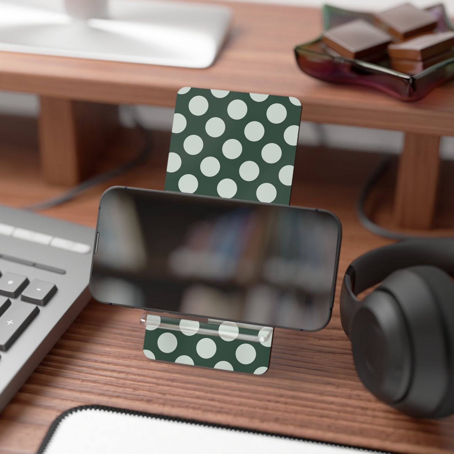 Green card with white polka dots on a desk with a phone, keyboard, and headphones.