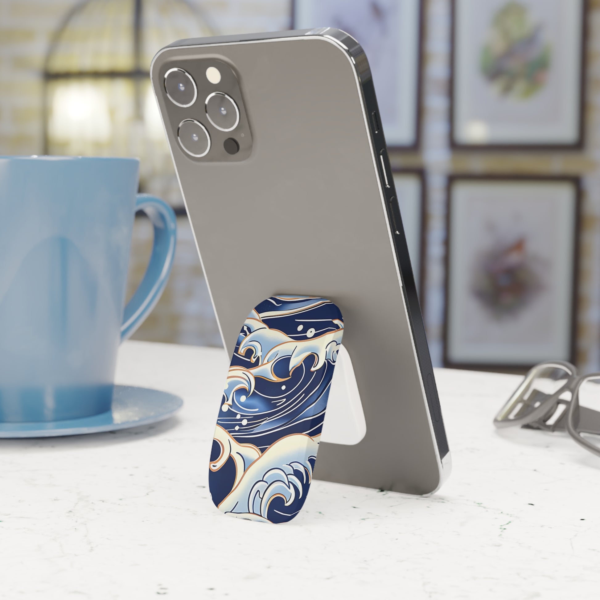 Phone case with wave design on a phone held by a stand, next to a blue mug.