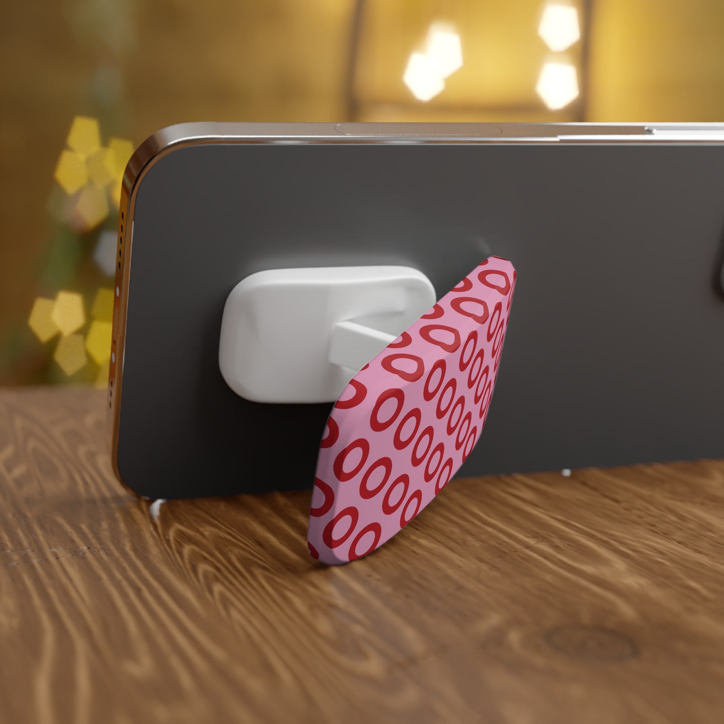 Phone with a pink and red patterned stand on a wooden surface