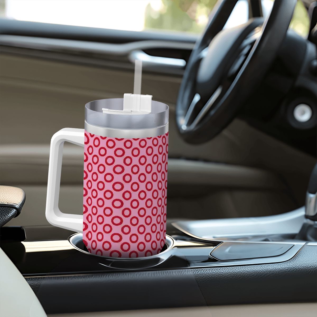 Pink polka dot mug with a straw on a car cup holder
