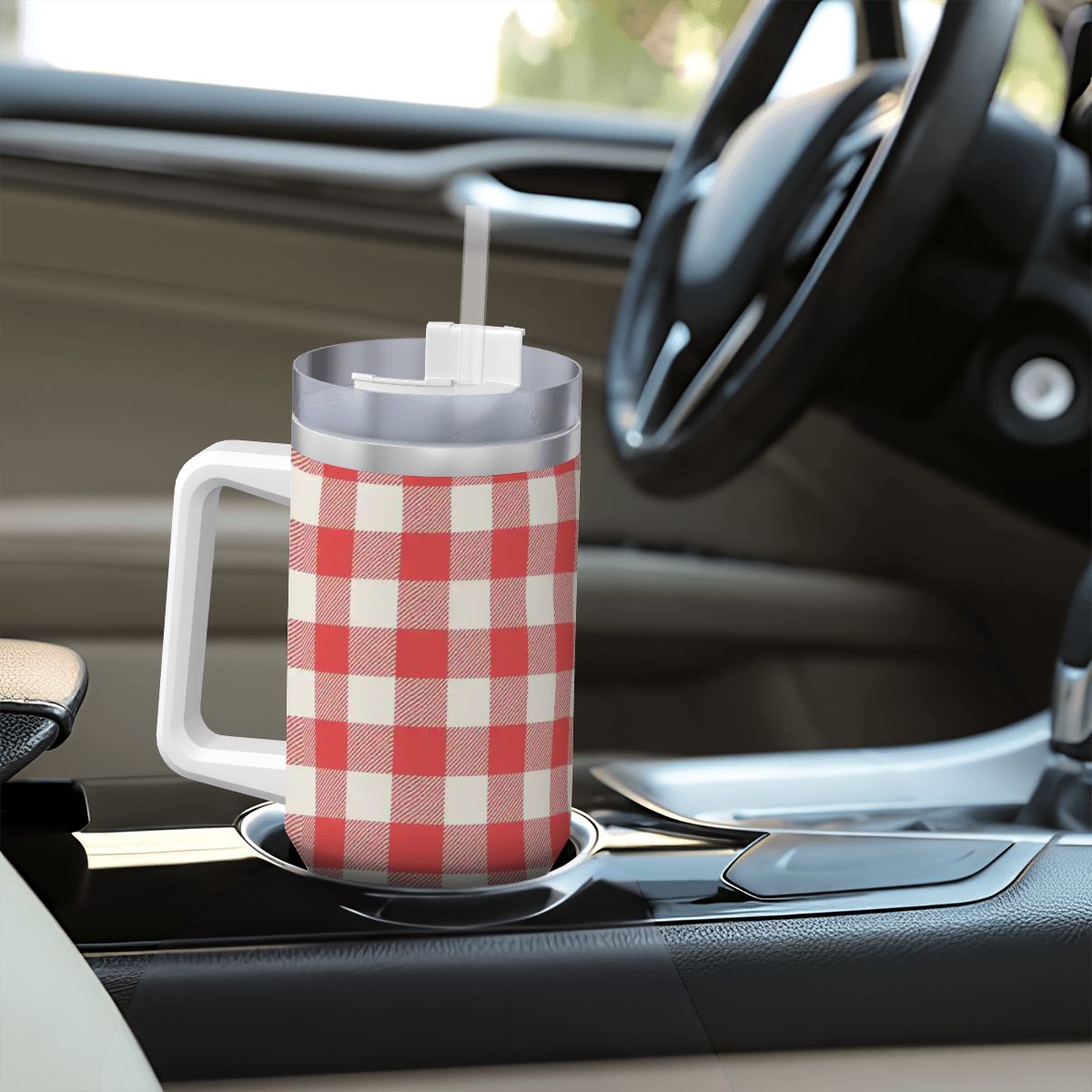 Red and white checkered mug with a straw on a car cup holder