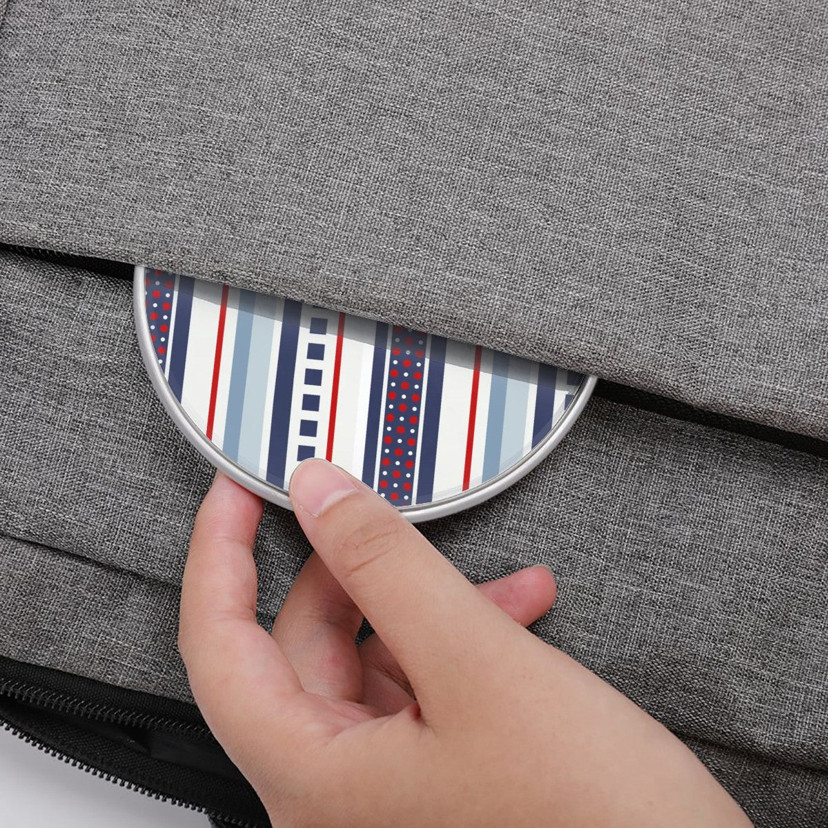 Hand placing a striped coaster into a gray fabric bag