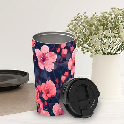 Travel mug with pink floral design on a white surface with a vase of flowers in the background.