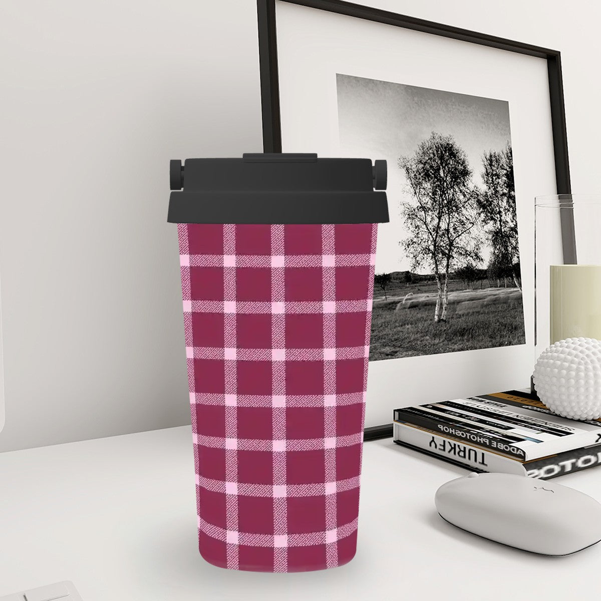 Plaid-patterned tumbler on a desk with a framed picture in the background