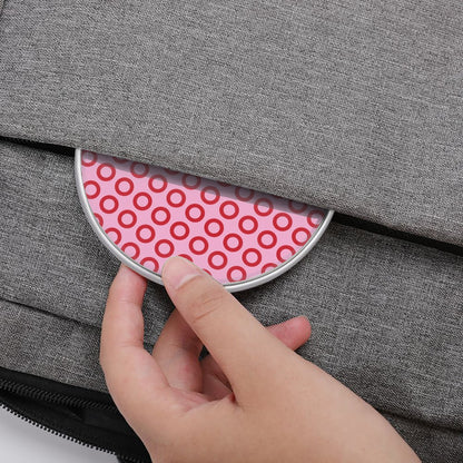 Hand opening a gray bag with a pink circular patterned compartment.