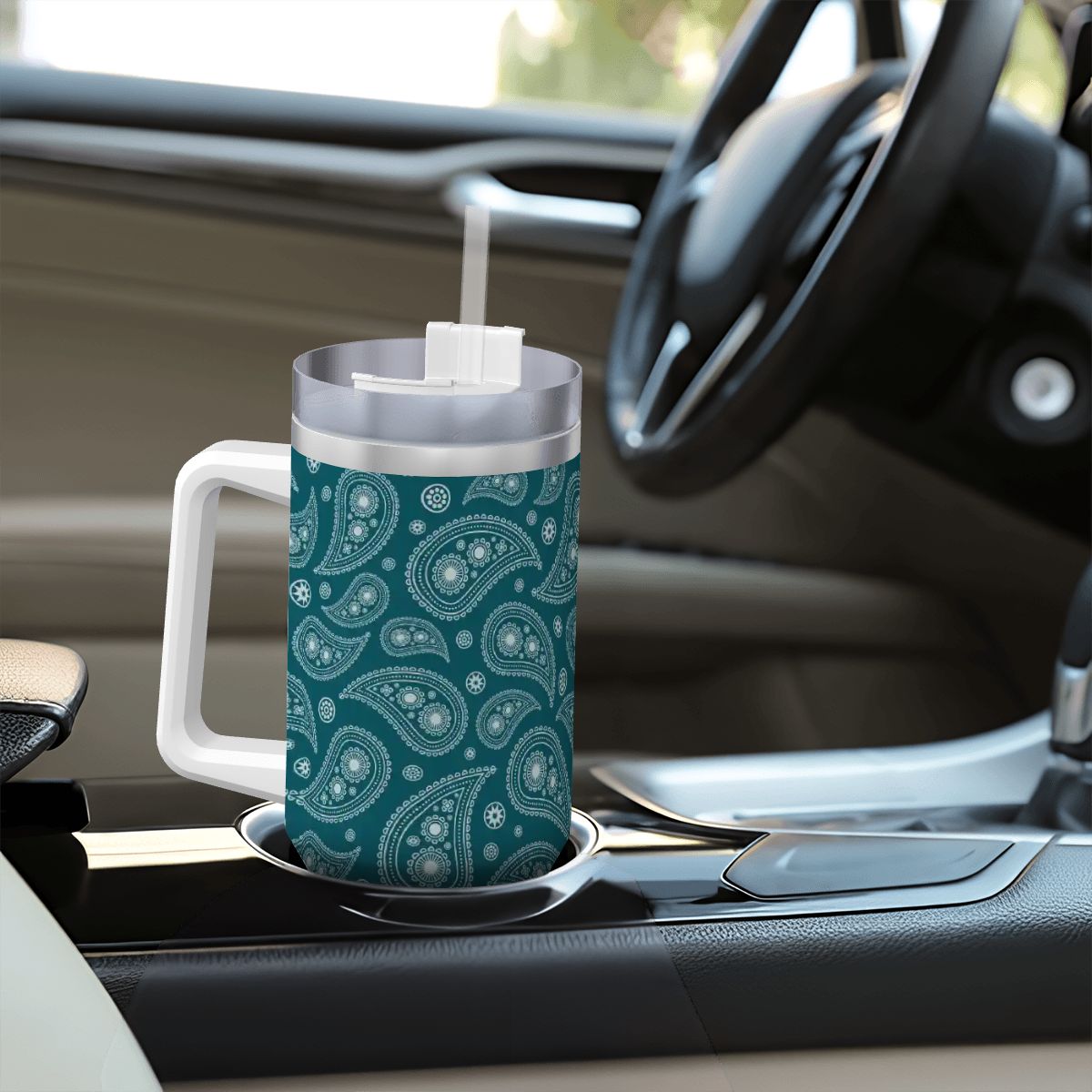 Teal paisley-patterned mug with a straw on a car dashboard
