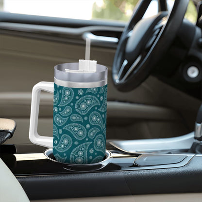 Teal paisley-patterned mug with a straw on a car dashboard