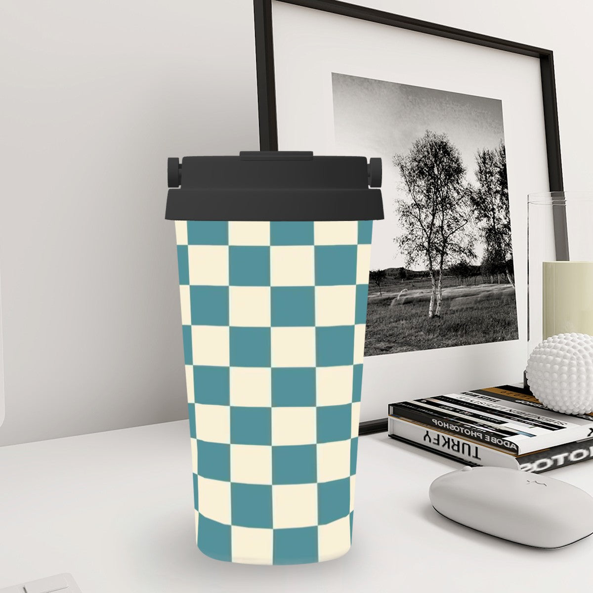 Checkered patterned tumbler on a desk with a framed picture in the background