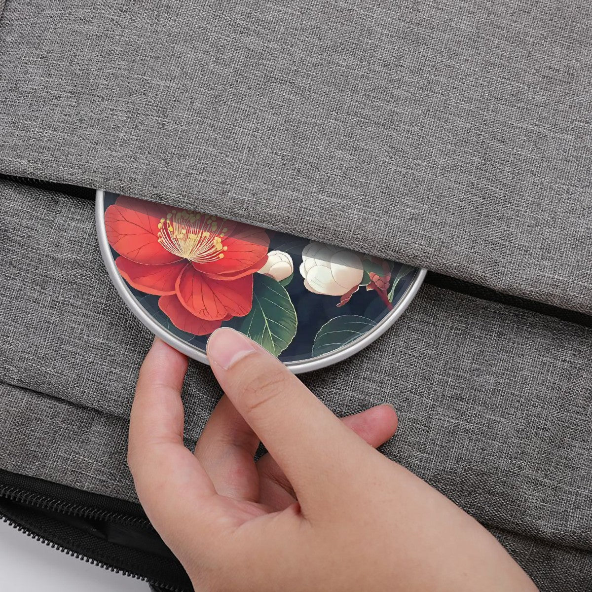 Hand opening a gray fabric case with a floral compact mirror peeking out.