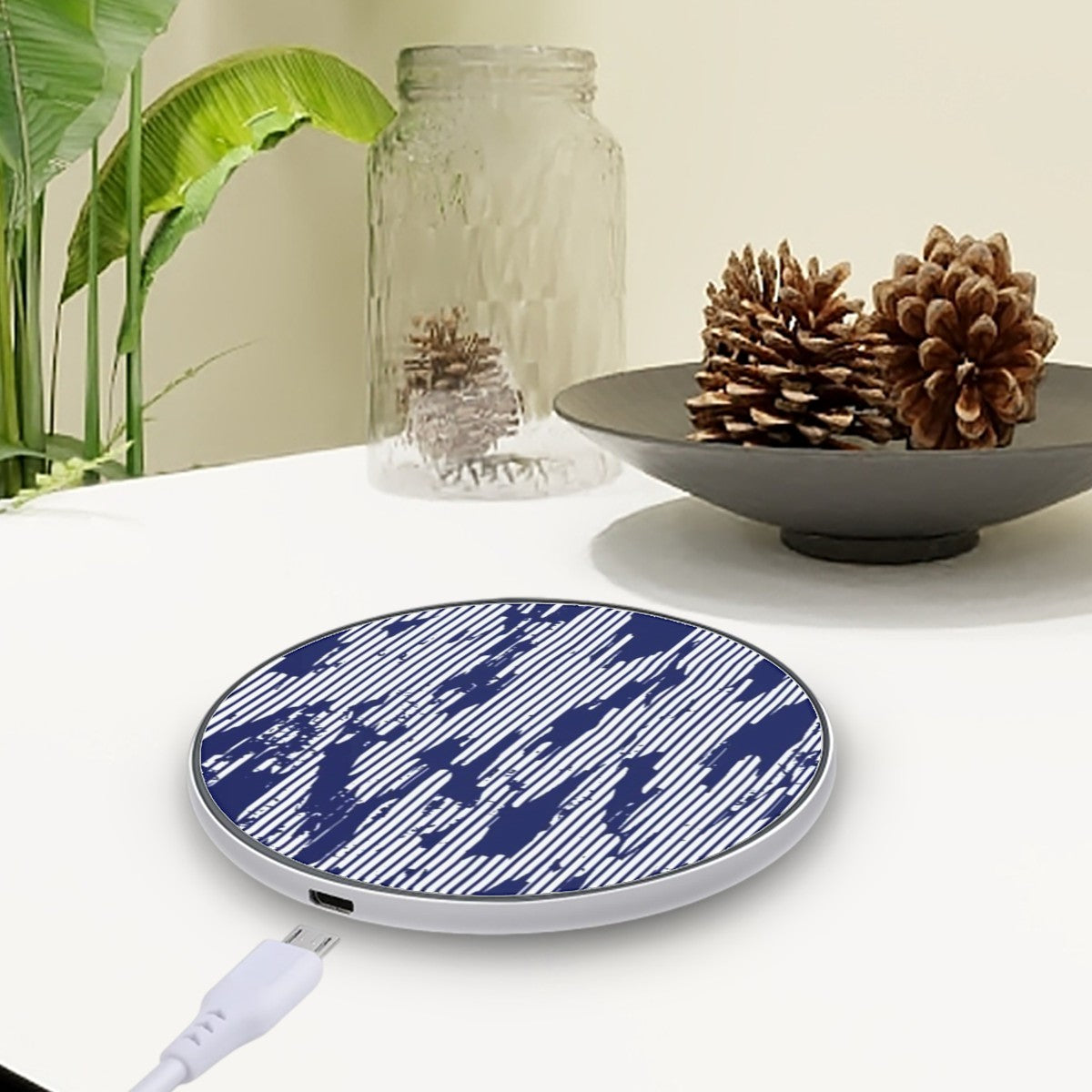 Wireless charging pad with blue pattern on a white surface with decorative items.