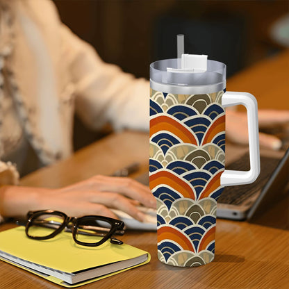 Colorful patterned mug with handle on a desk next to glasses and a notebook