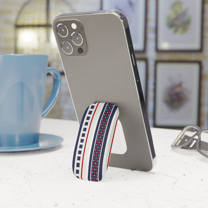 Phone stand with striped design holding a smartphone next to a blue mug on a table.