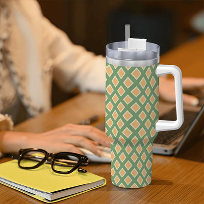 Person using a laptop with a patterned tumbler on a desk