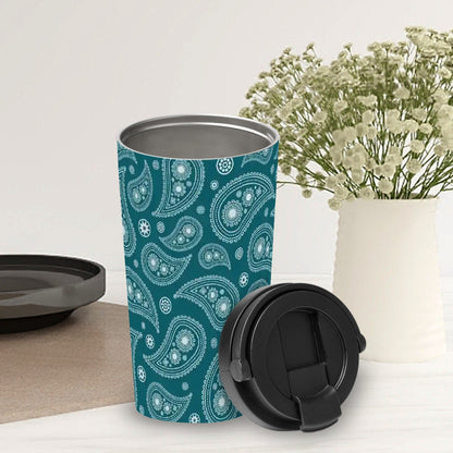 Teal paisley patterned tumbler with black lid on a white surface with a vase of flowers in the background.