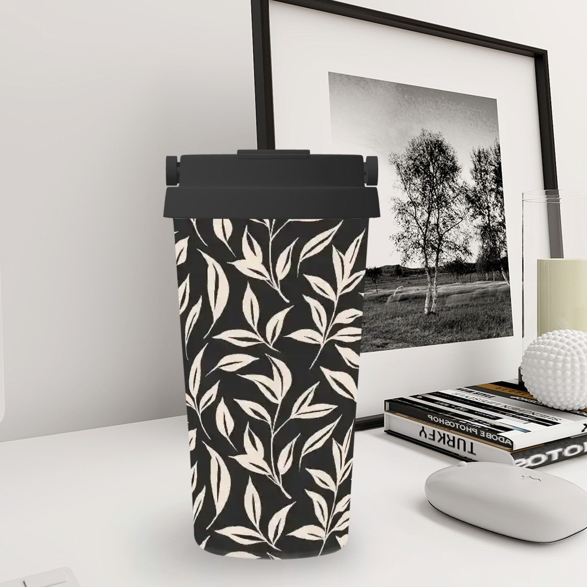 Black and white patterned can on a desk with a framed picture and books in the background
