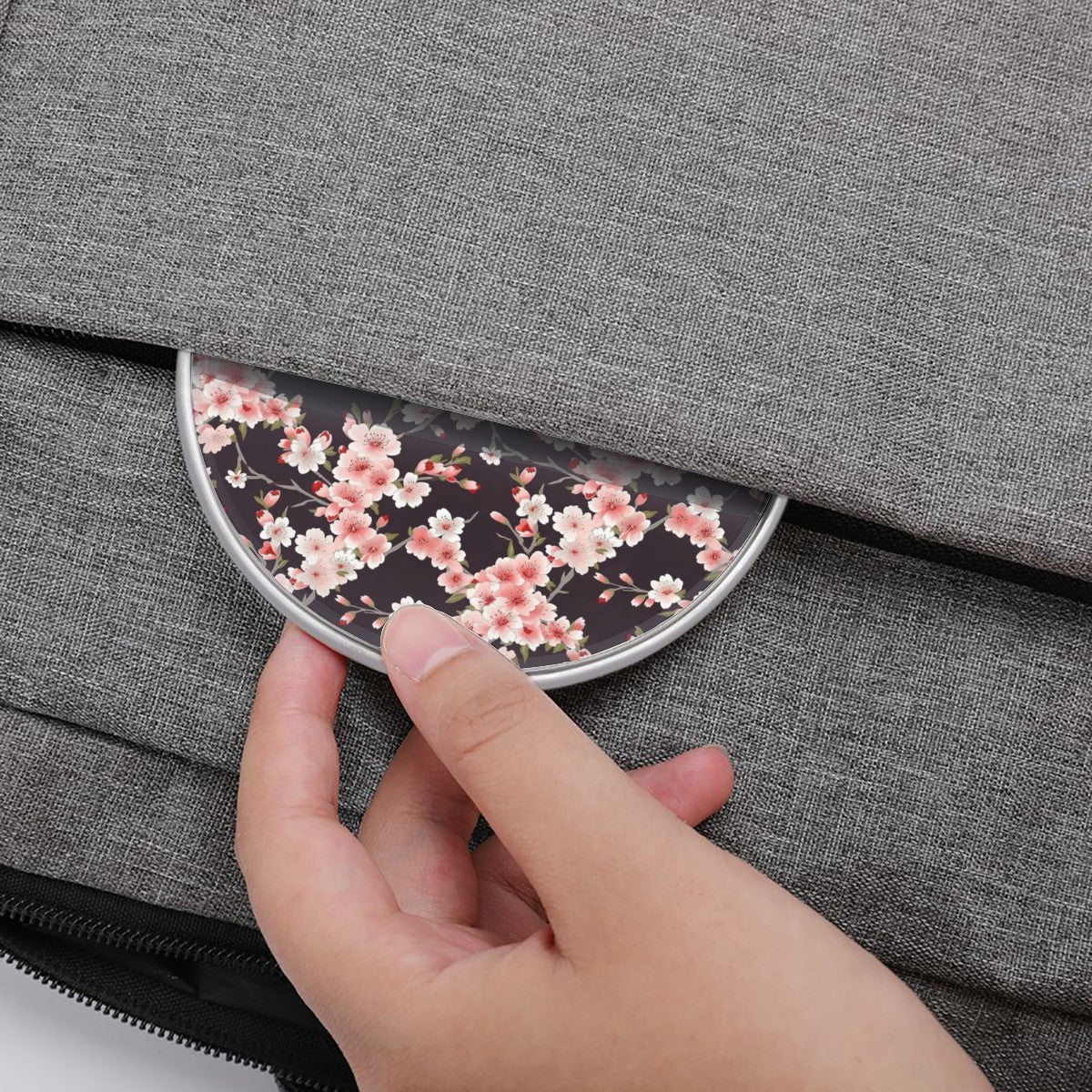 Hand placing a floral Wireless Charger into a gray bag