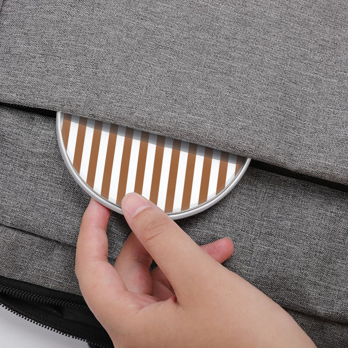 Hand opening a gray textured bag with a striped pattern