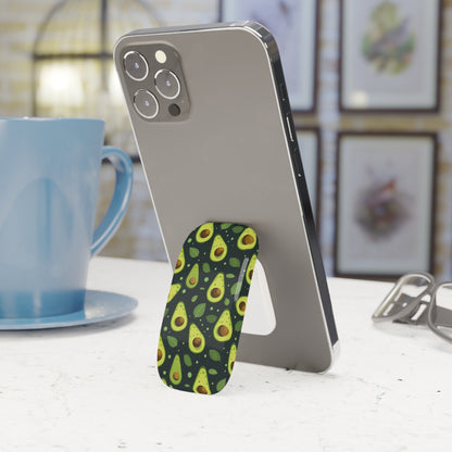 Phone with an avocado-patterned stand on a table next to a blue mug.