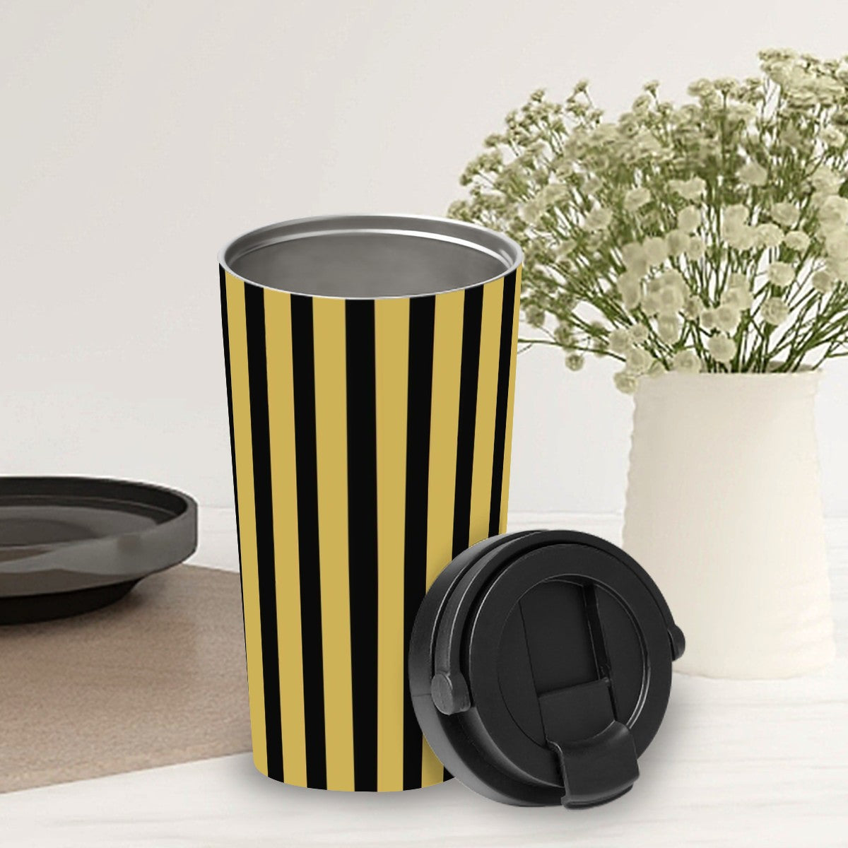Black and yellow striped travel mug with a black lid on a white surface.
