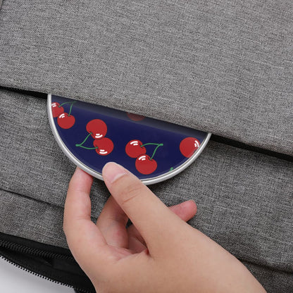 Hand holding a compact mirror with cherry design against a gray textured background
