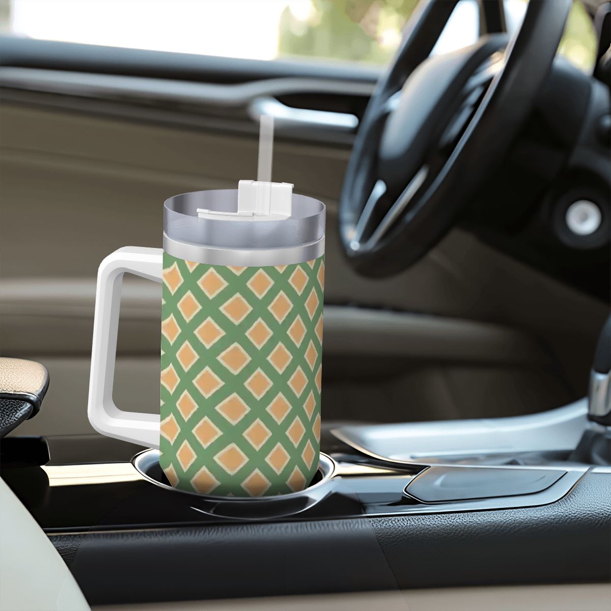 Green and orange patterned mug with a straw on a car dashboard